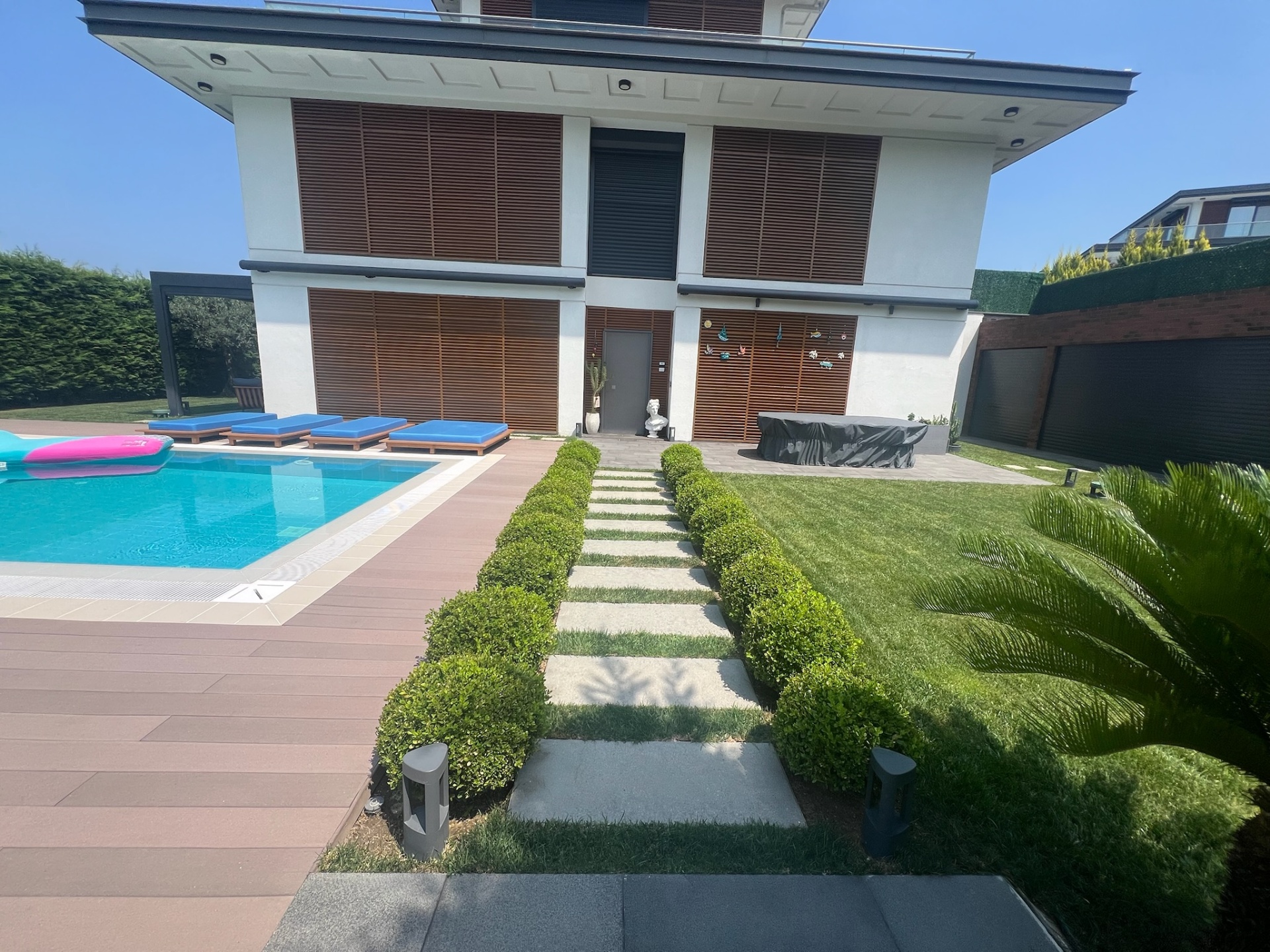 Full villa terrace — composite deck, boxwood-lined stone path and formal pool.