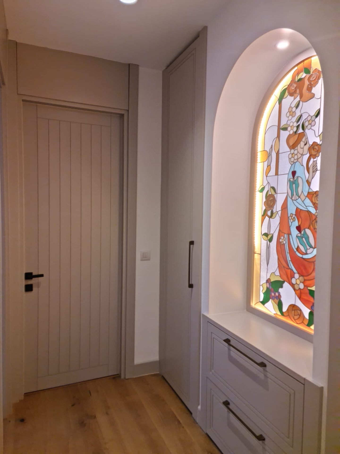 Fluted ivory pocket door beside a backlit stained-glass niche