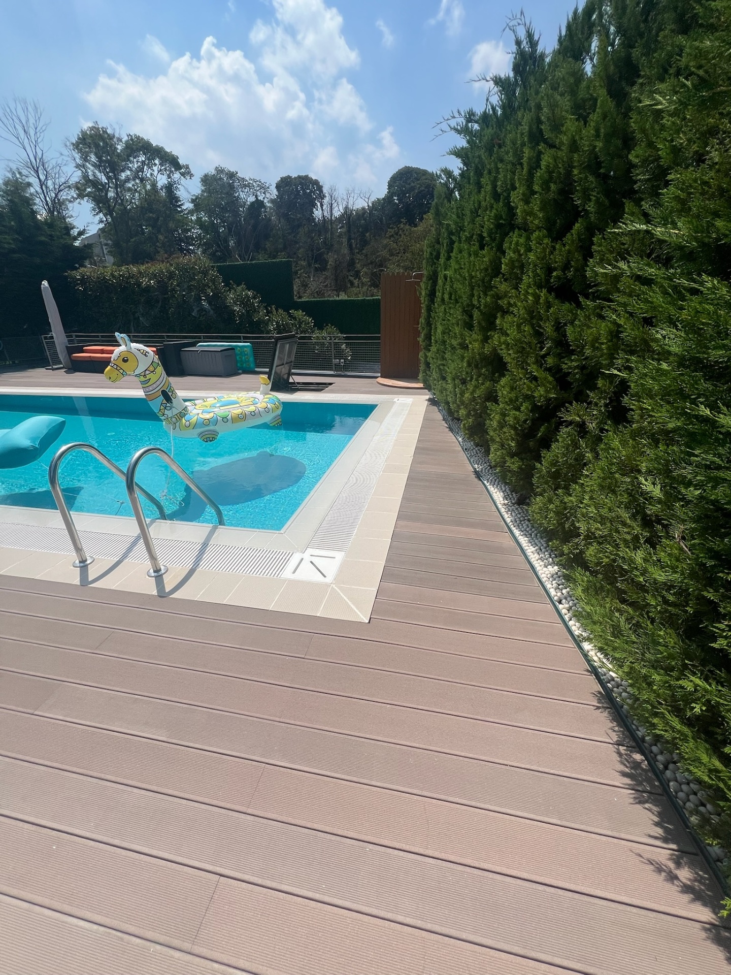 Composite hardwood pool deck with concealed technical hatch and cypress screen.