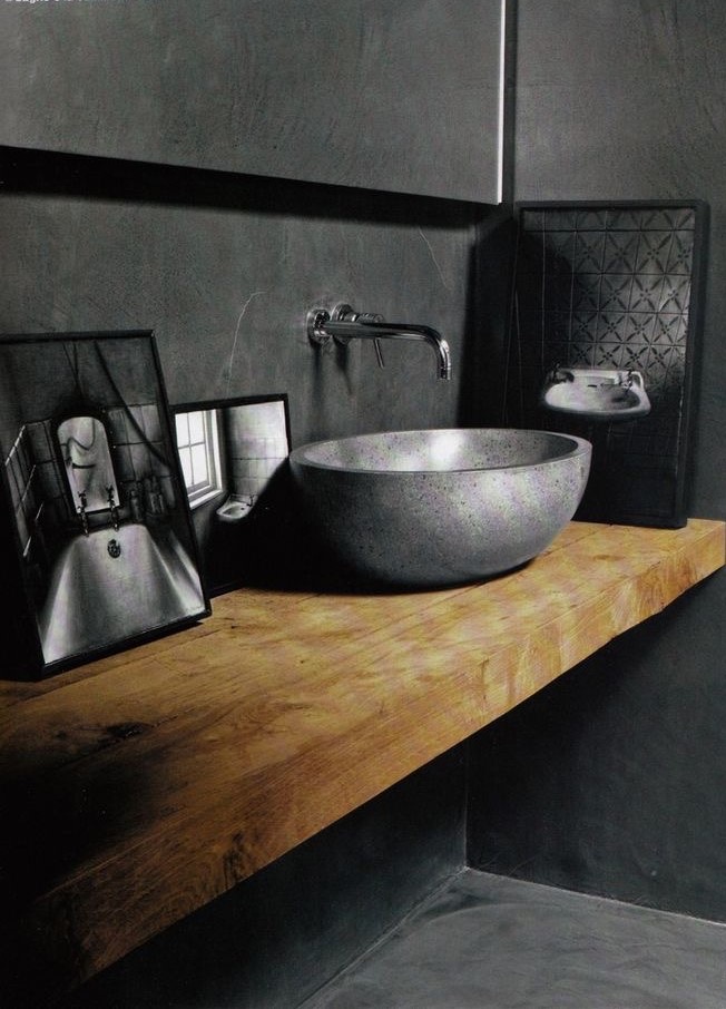Solid oak floating slab with cast stone vessel against blackened plaster wall