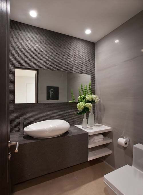 Ribbed charcoal feature wall with monolithic stone vanity and sculptural vessel basin.