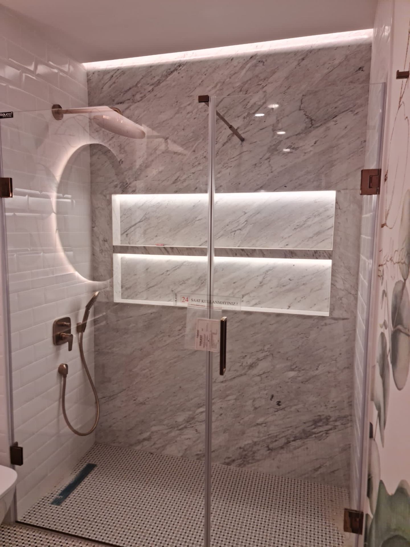 Frameless glass shower enclosure with book-matched Carrara marble and recessed LED niches