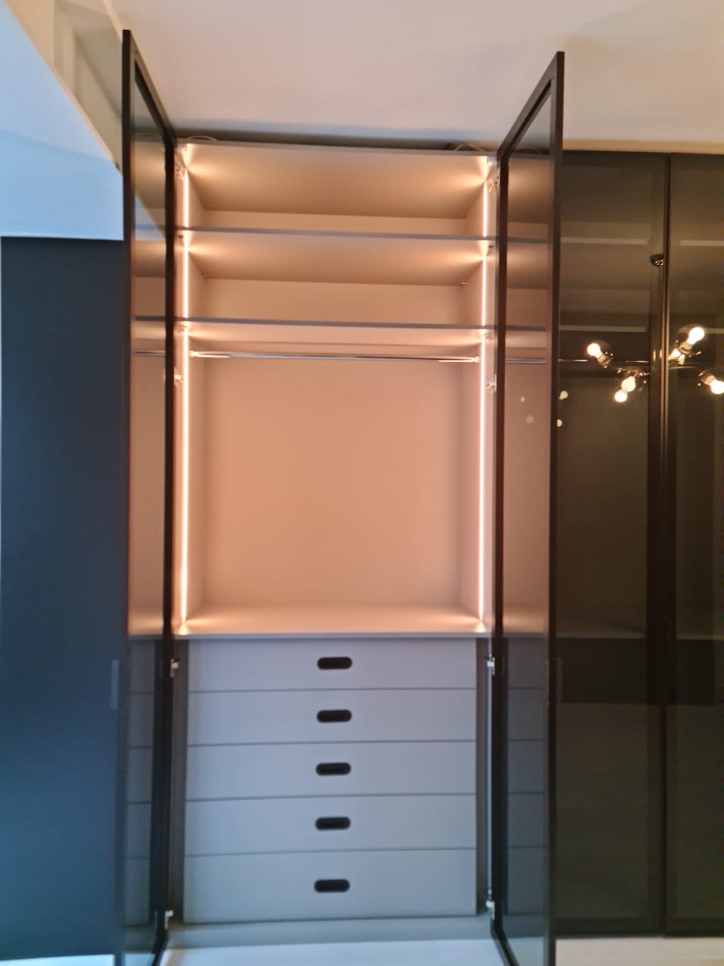 Illuminated shelving with dark metal frames and soft-close drawers