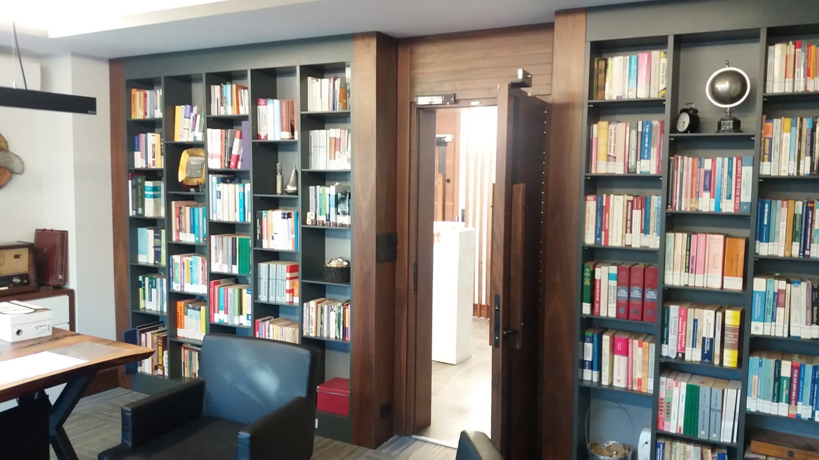Walnut pivot door integrated into a floor-to-ceiling library wall