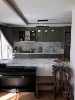 Sage green kitchen with book-matched marble backsplash and fluted island