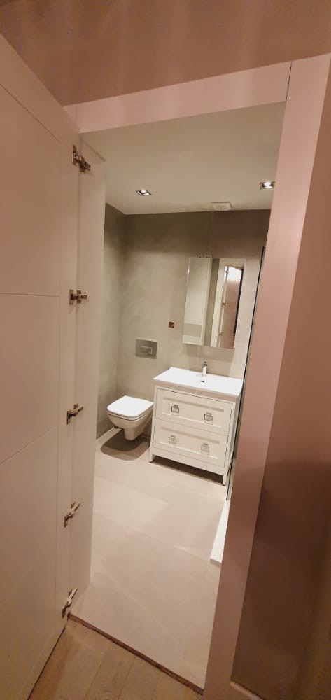 Compact guest cloakroom with rose-blush ceiling and slim ivory vanity