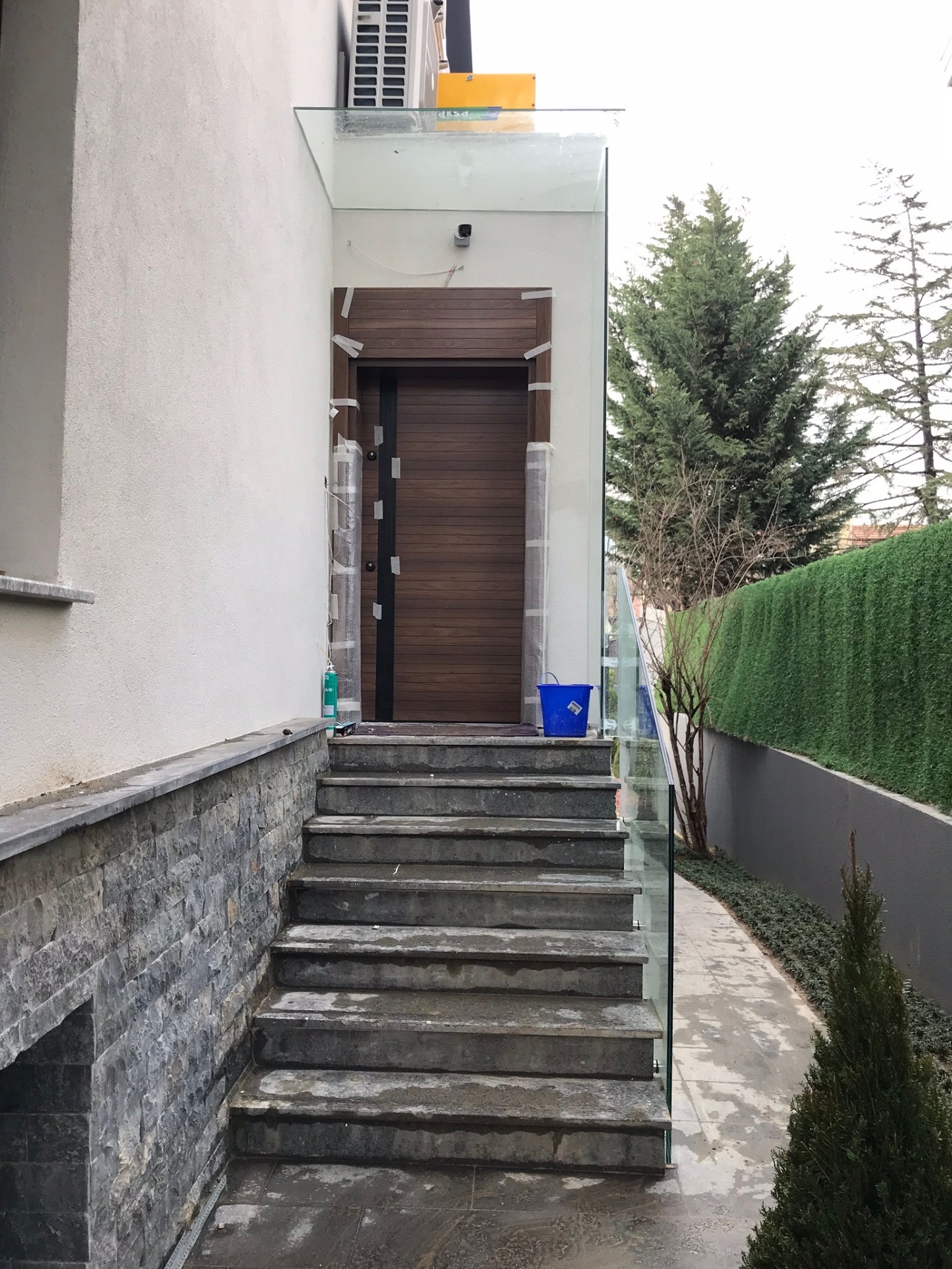 Slatted walnut entrance door beneath a glass canopy — private villa