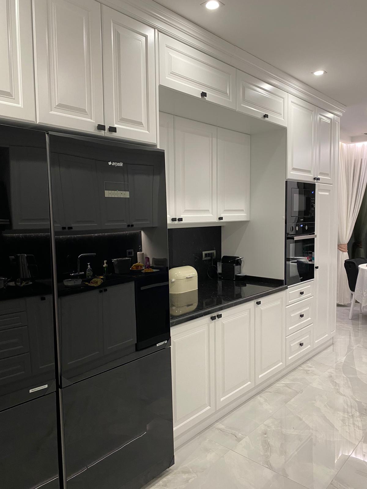 Framed white lacquer kitchen with black granite worktop and matt black hardware