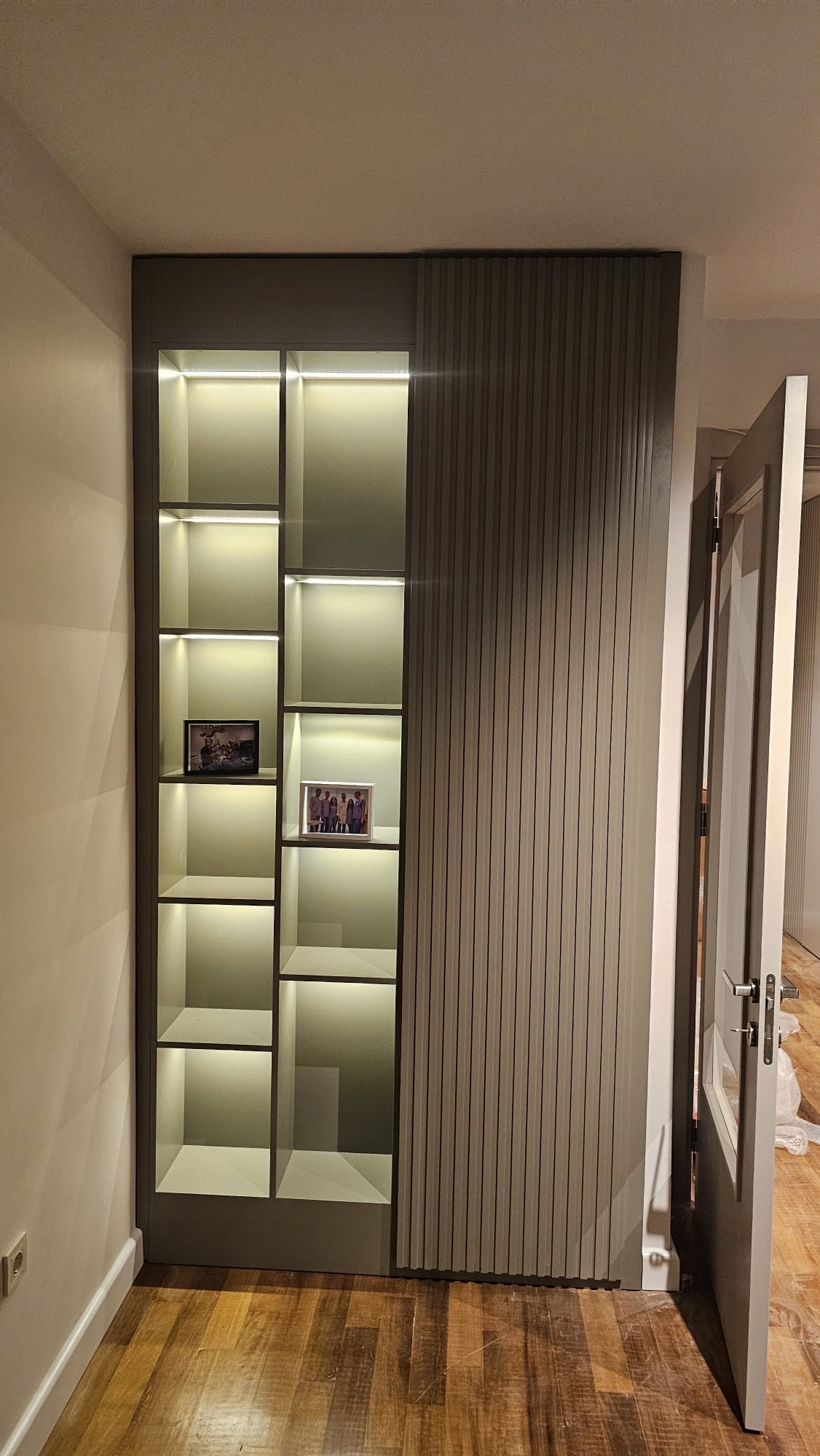 Graphite display wall with backlit vitrine and fluted panelling