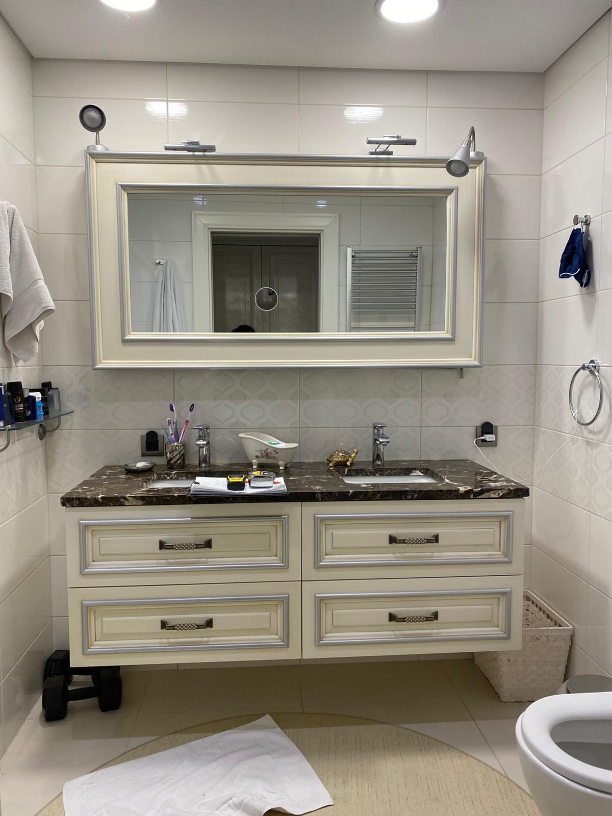 Ivory & silver-leaf twin-basin vanity with emperador marble top and gallery lighting.