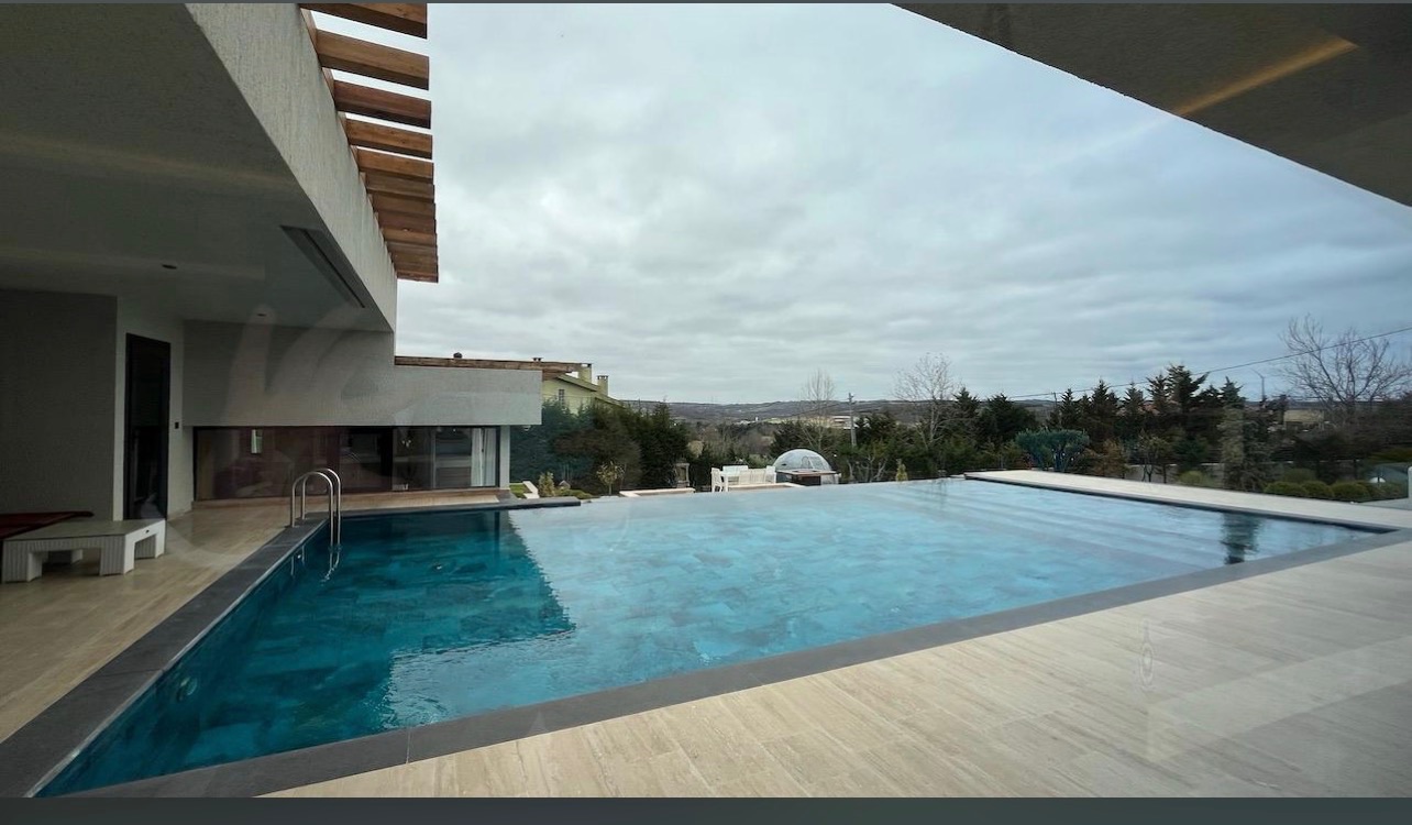 Infinity-edge villa pool with travertine deck and framed valley view.