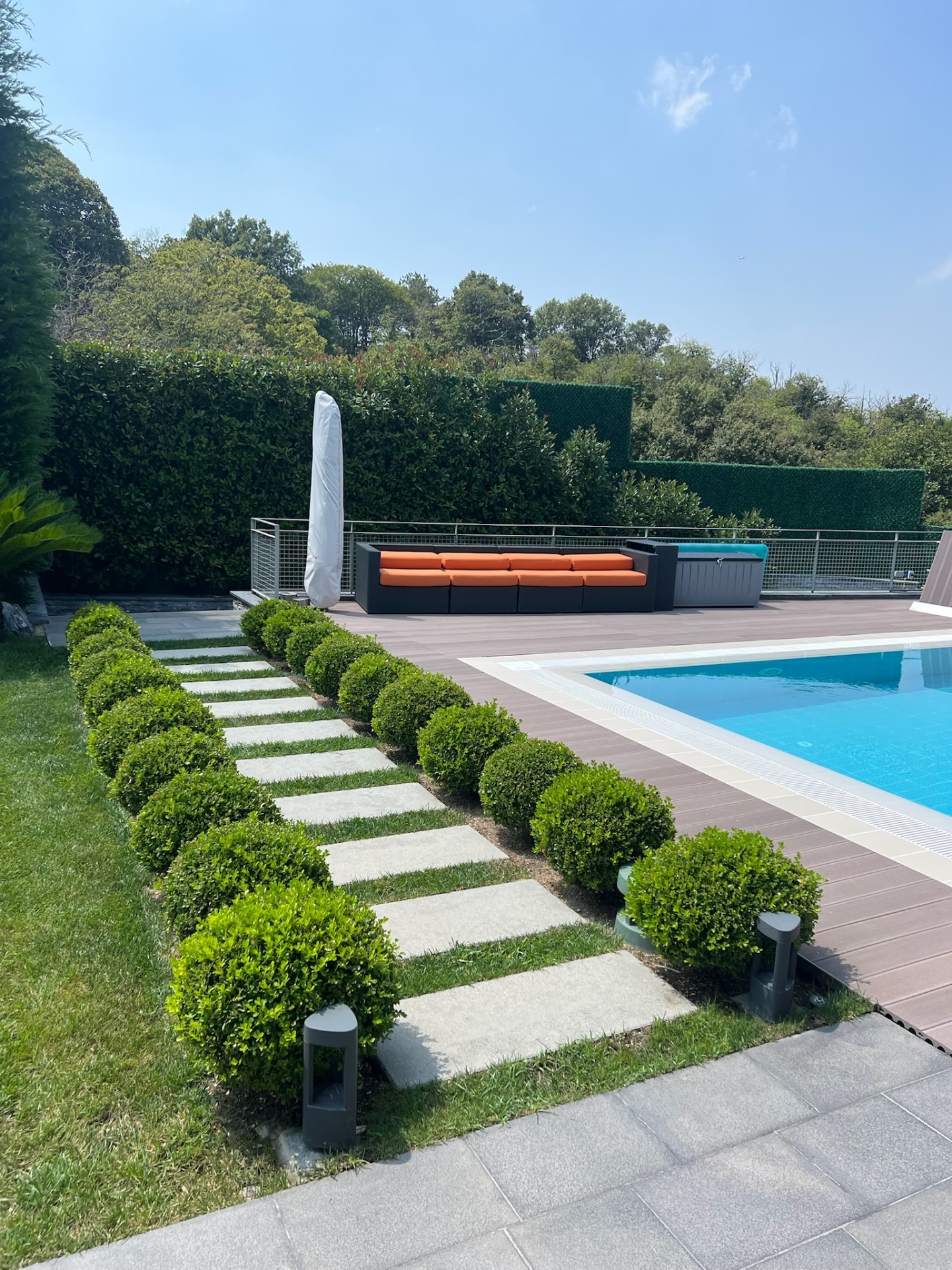 Formal boxwood alley leading to outdoor lounge and pool terrace.