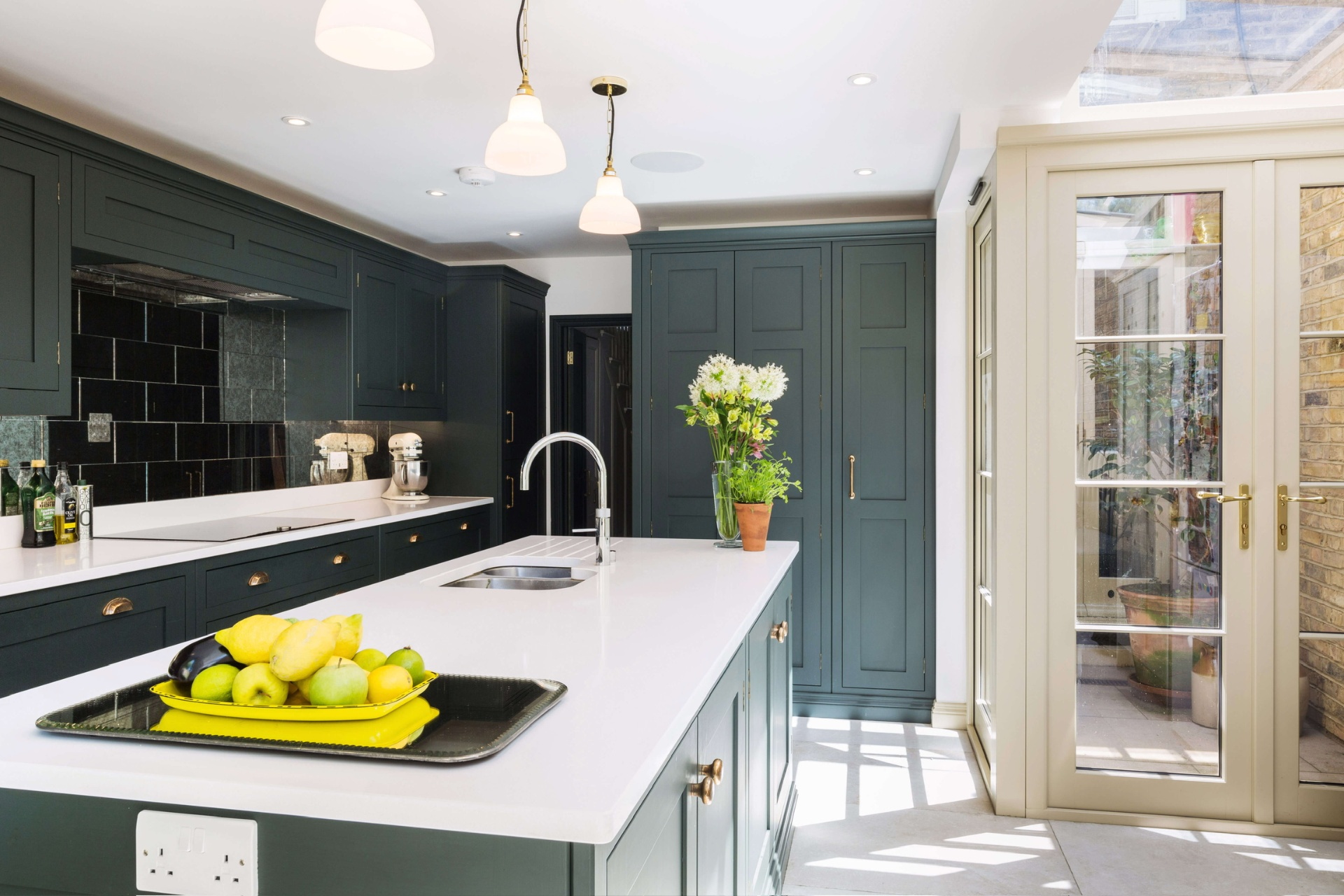 Forest green in-frame kitchen with quartz island and garden orangery