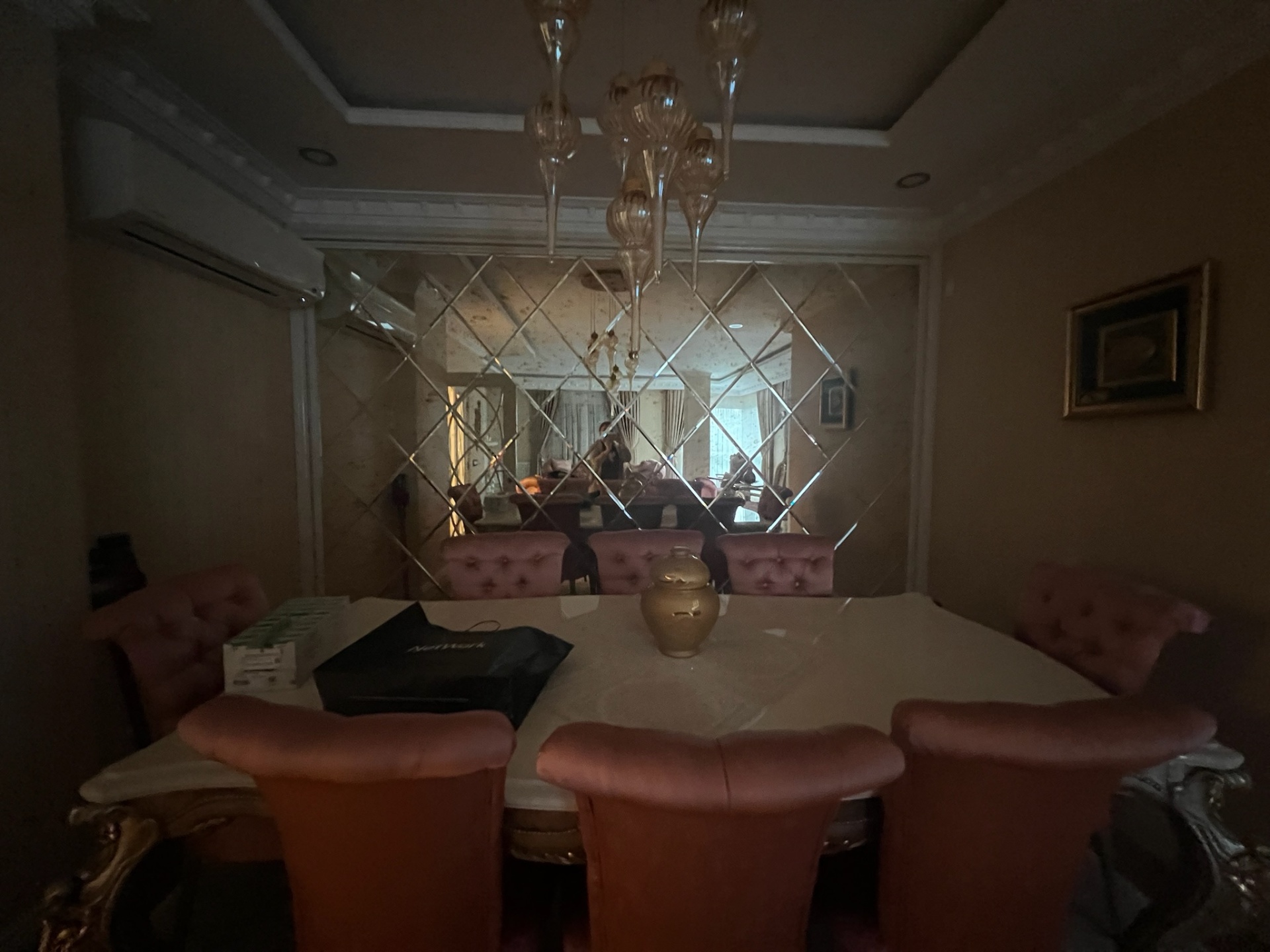 Formal dining table under Murano chandelier, mirrored feature wall