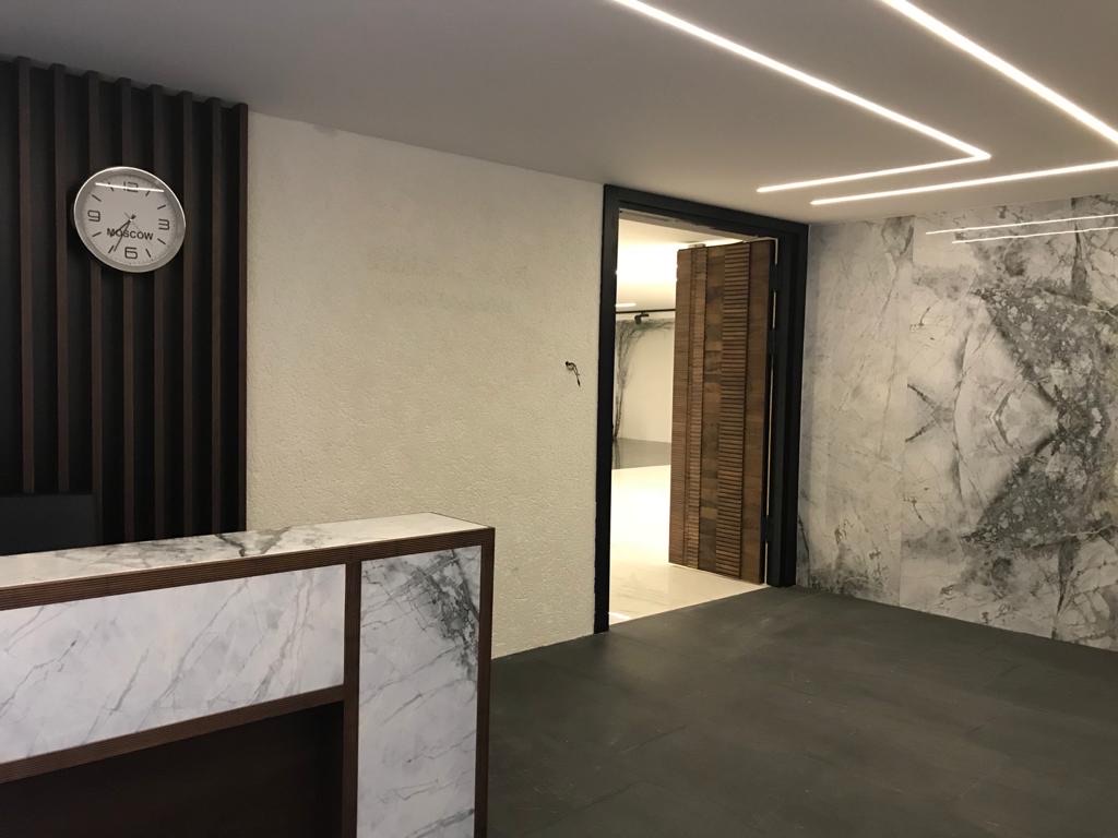 Slatted walnut double door framed in blackened steel between marble and stone