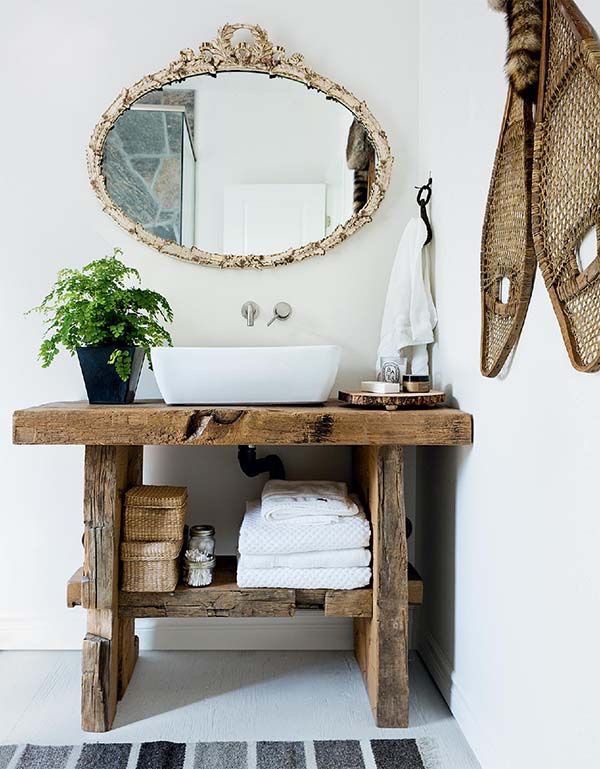 Hand-hewn reclaimed timber console beneath a carved gilt oval mirror.