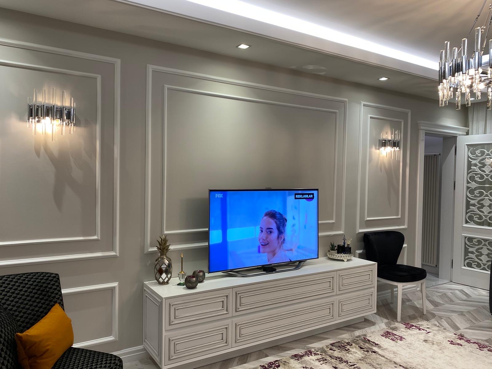 Classical panelled media wall with wainscoting and crystal sconces